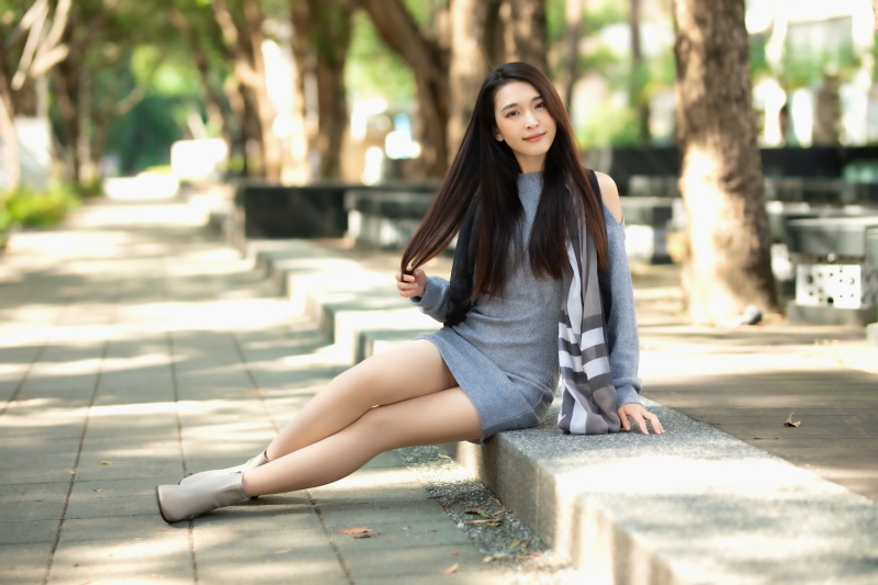 Asian woman sitting on a ledge outdoors