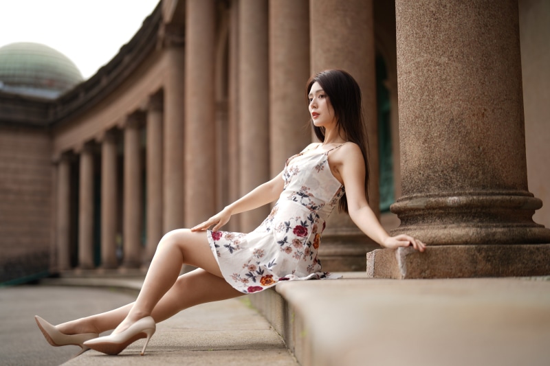 Asian woman in floral dress sitting by columns