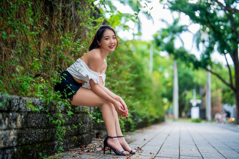 Asian woman sitting on a stone wall