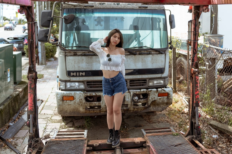 Asian woman in shorts and blouse standing by a truck