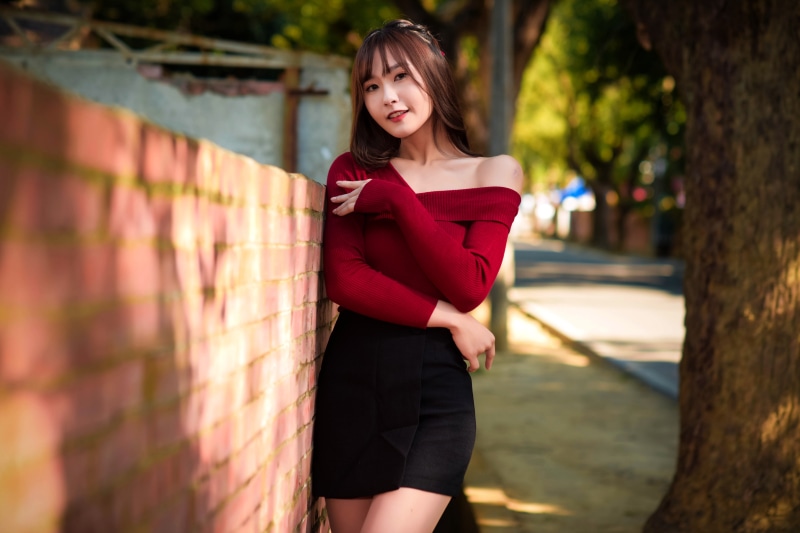 Asian woman in red off-shoulder blouse and black skirt