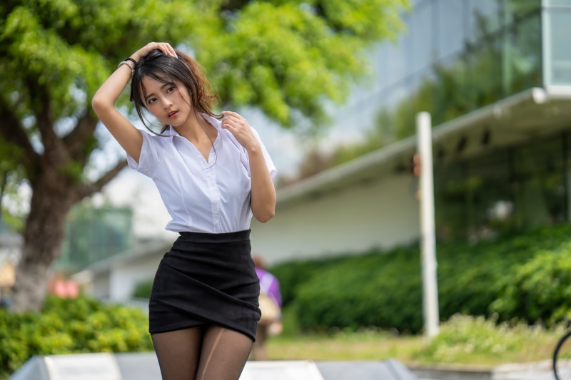 Asian woman in blouse and skirt posing outdoors
