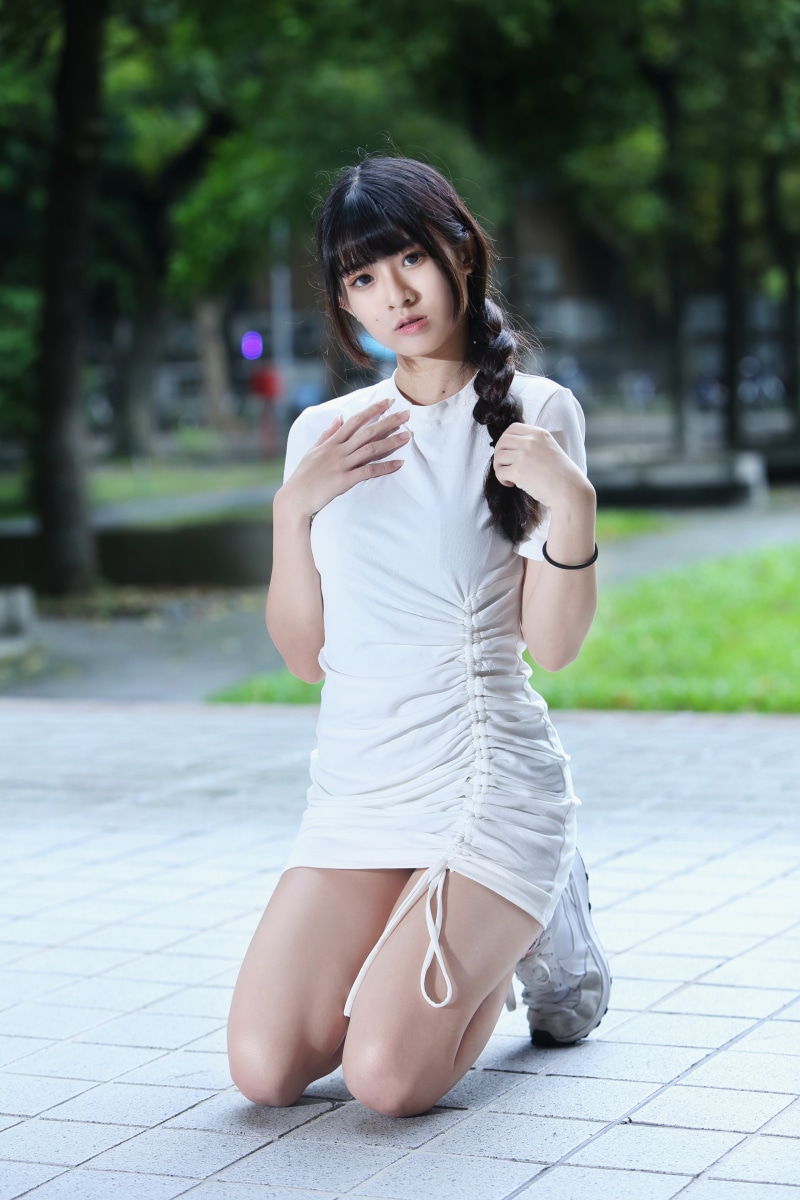 Asian woman with braid hair kneeling in a white dress