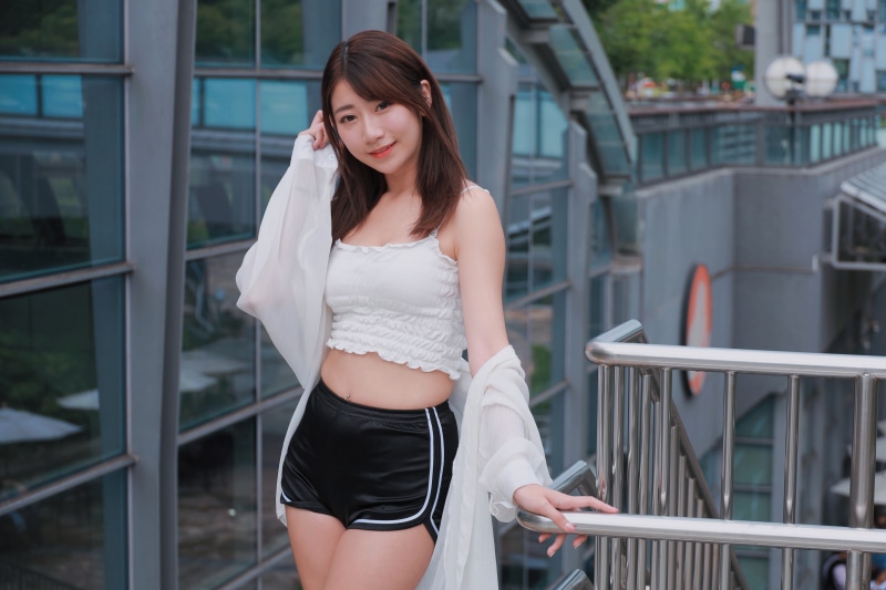 Asian woman in white singlet and black shorts posing