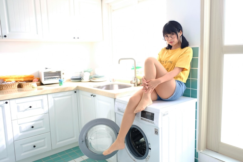 Brunette girl with glasses sitting on washing machine