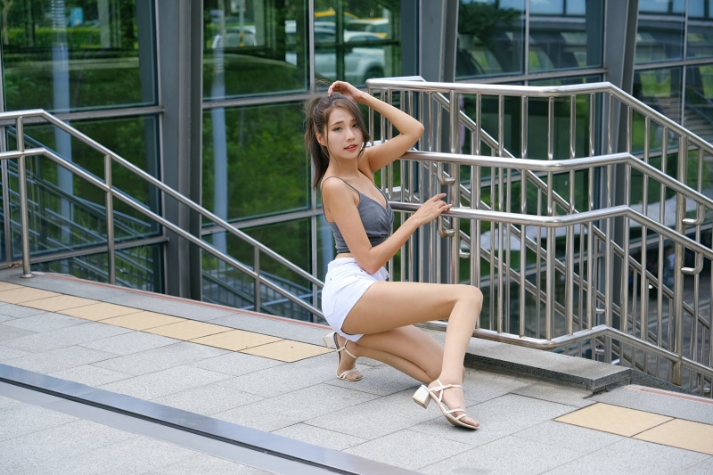 Asian woman in shorts and singlet posing on stairs