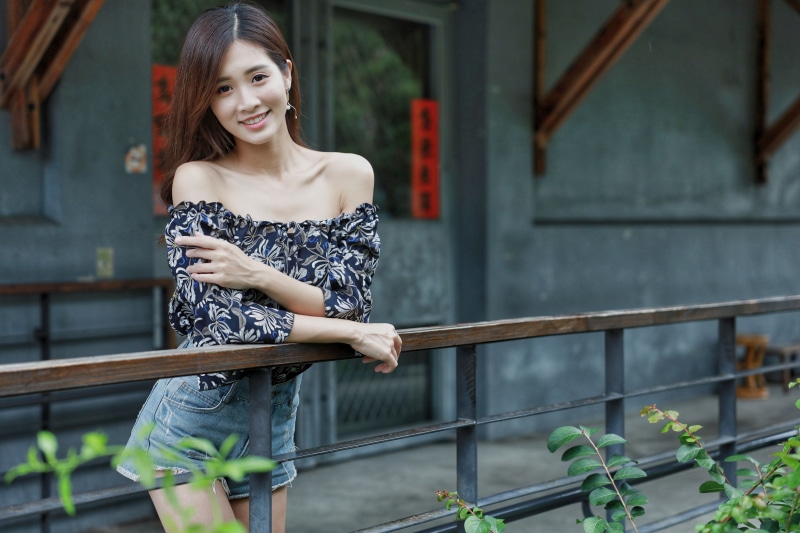Asian woman in off-the-shoulder blouse and shorts