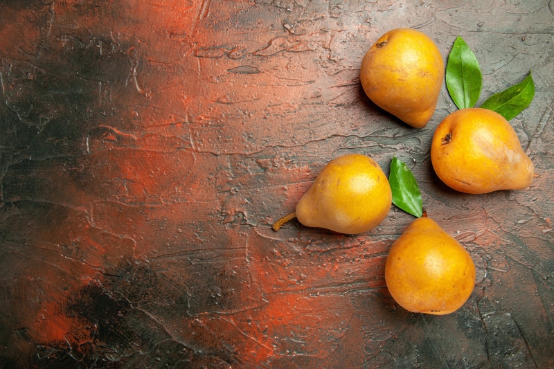 Four Pears with Leaves on Textured Surface