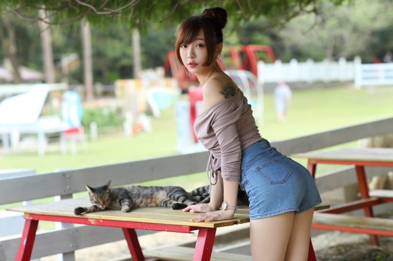 Asian woman in shorts and blouse with cat