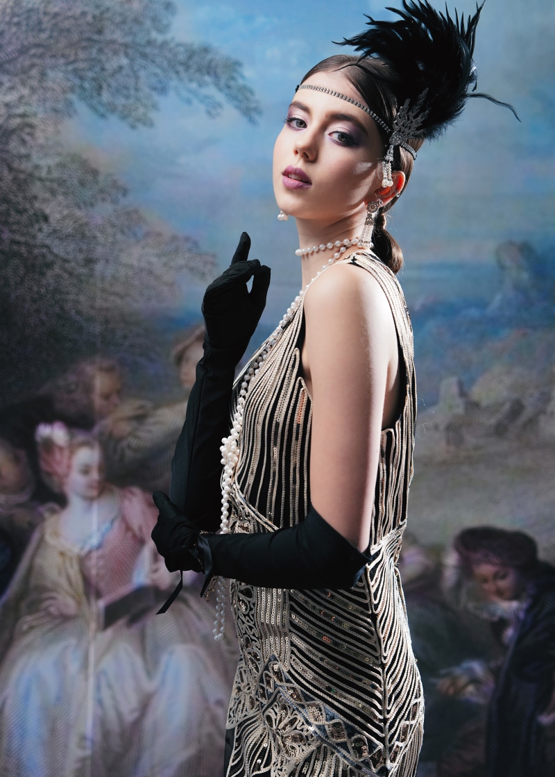 Woman in 1920s attire with pearls and gloves