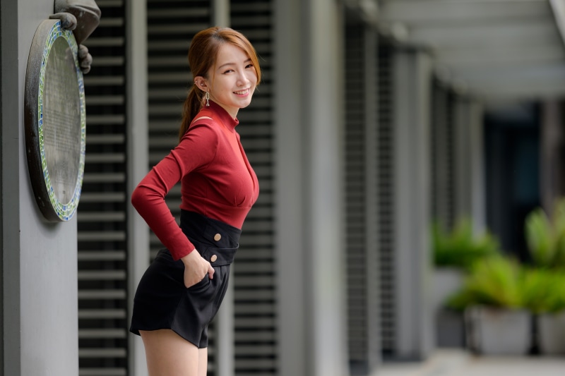 Asian woman in red blouse and black shorts posing