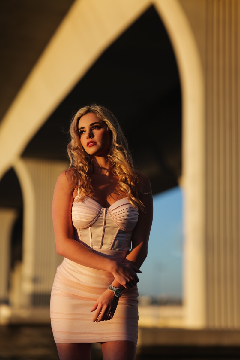 Blonde girl in a dress posing under arches