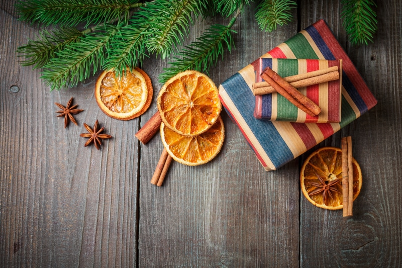 Christmas gifts with dried oranges and cinnamon on wood