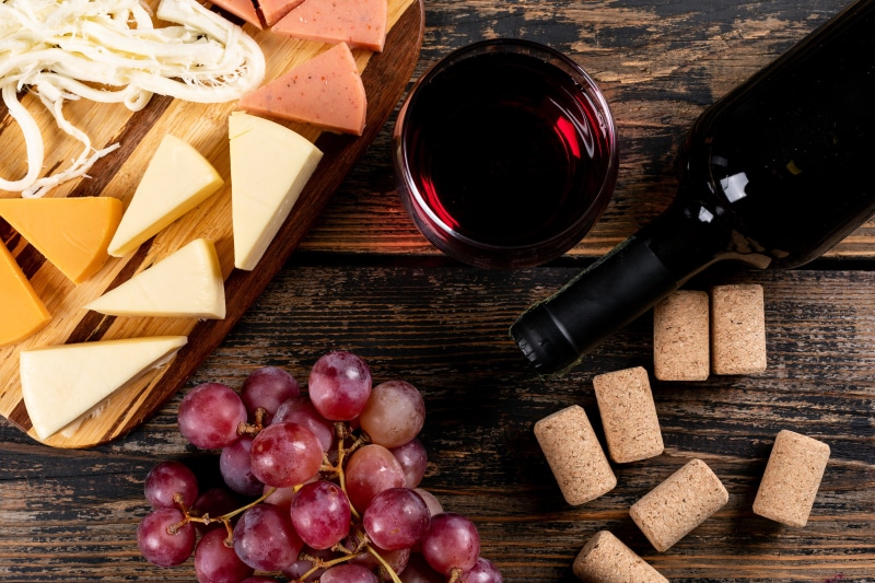 Wine bottle, glass, cheese, and grapes on a table