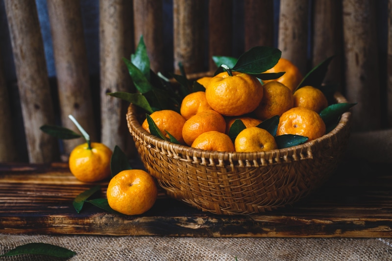 Mandarin oranges in a wicker basket with foliage