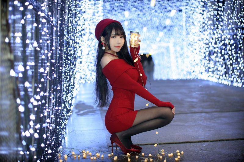 Brunette girl in red dress posing with fairy lights