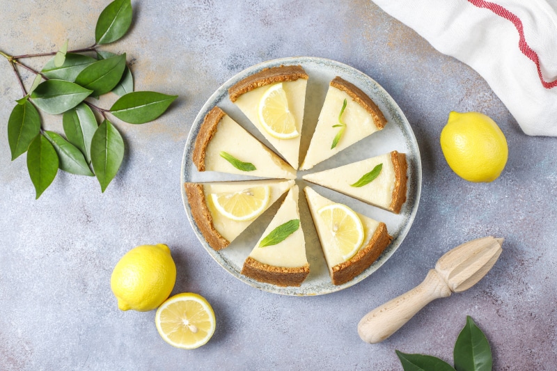 Lemon pie slices on a plate with lemons and foliage