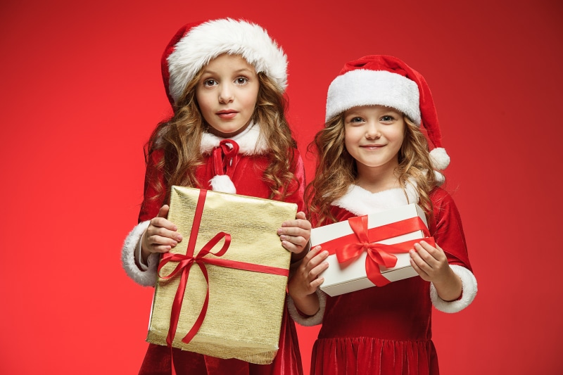 Two girls in Santa costumes with Christmas gifts