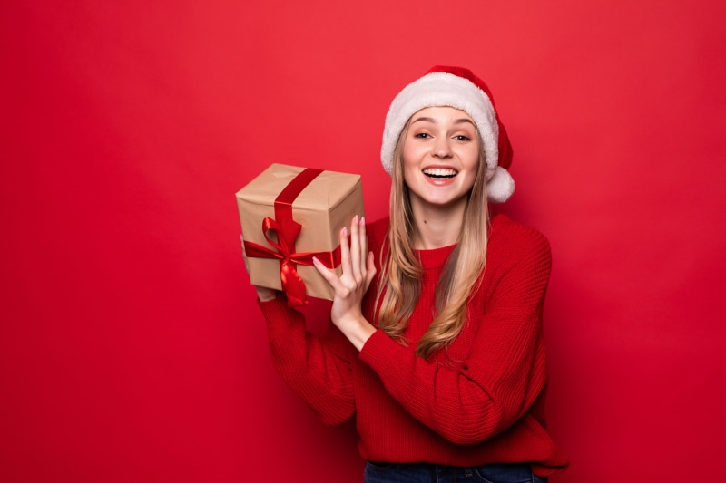 Woman in Santa hat holding a Christmas gift