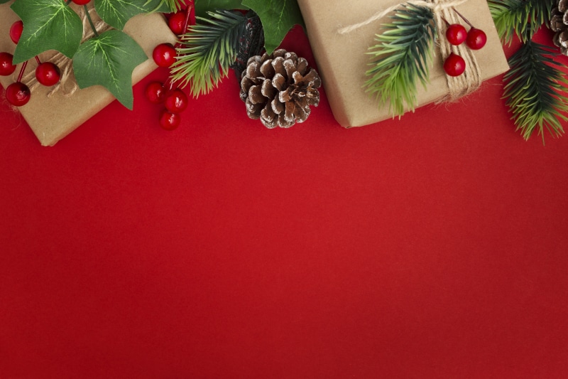 Christmas gifts with pine cones and branches on red background