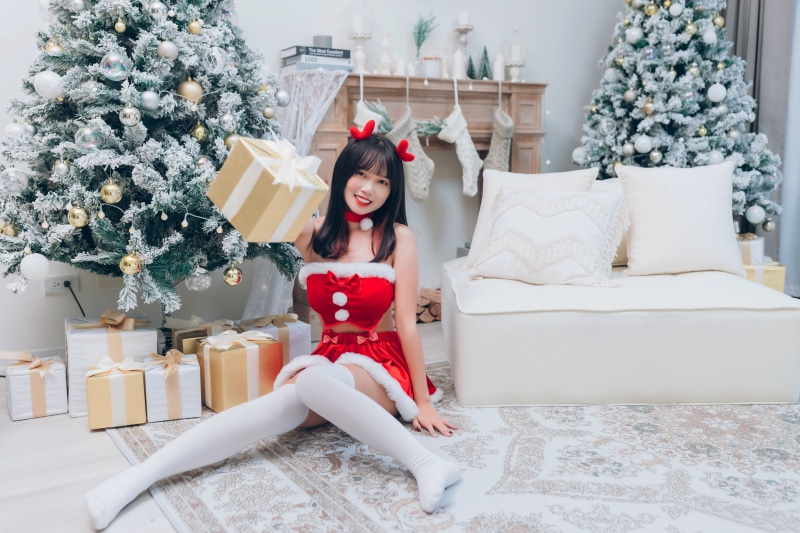 Asian woman in Christmas outfit holding gift box