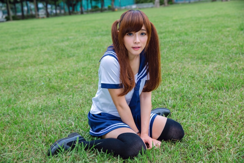 Asian girl in uniform sitting on grass