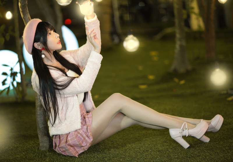 Yishuang wearing a pink beret and skirt sitting on grass