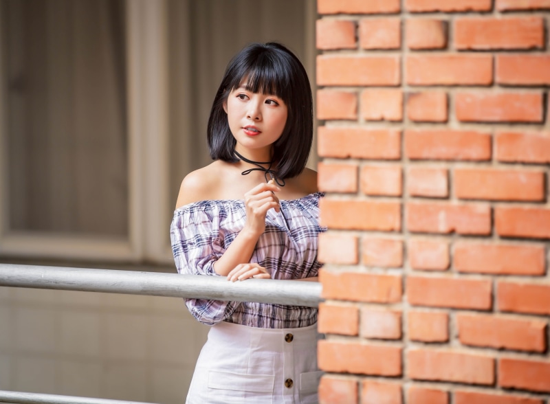 Asian girl with short black hair by brick wall