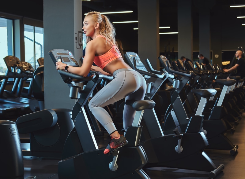 Blonde woman working out on a stationary bike in a gym
