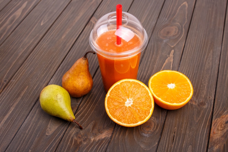 Orange juice with pears and oranges on wooden planks