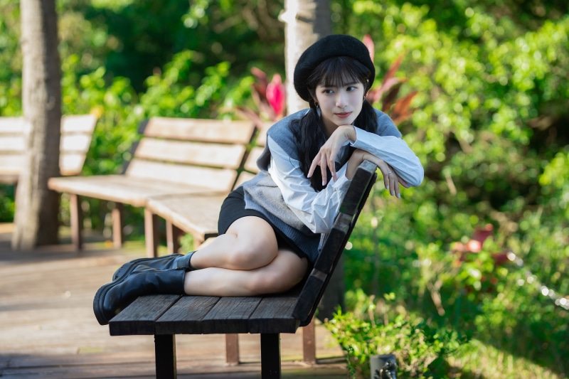 Asian woman in beret sitting on a park bench