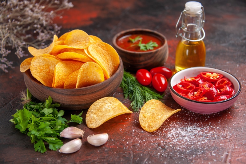 Potato chips with dipping sauce, chili, garlic, and tomatoes