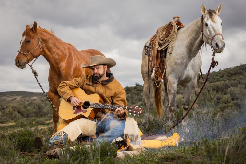 Cowboy playing guitar with horses