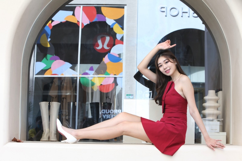 Asian woman in red dress sitting by a shop window
