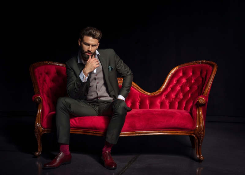 Man in Suit Sitting on Red Sofa