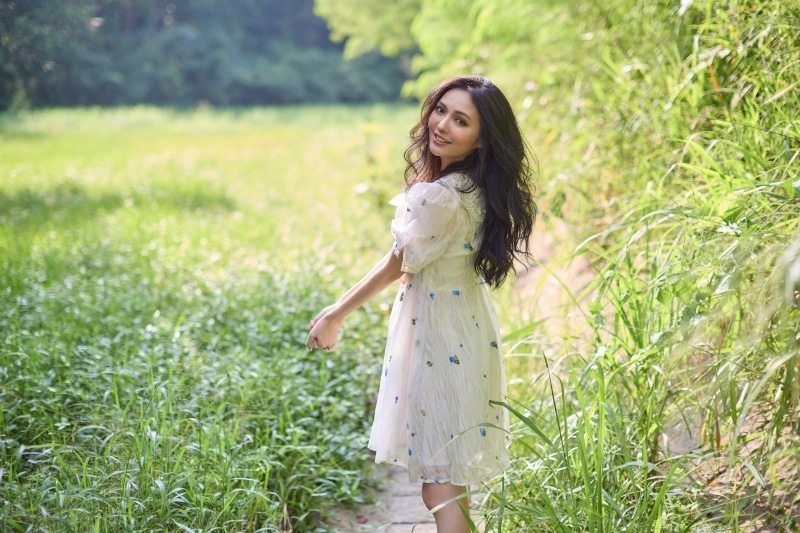 Asian woman in a white dress posing in a grassy field