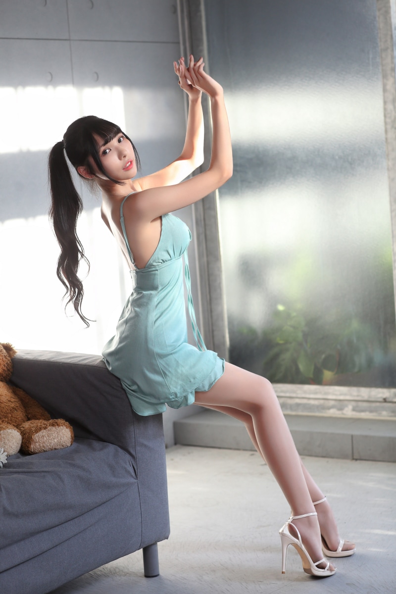 Asian woman in a light blue dress posing on a couch