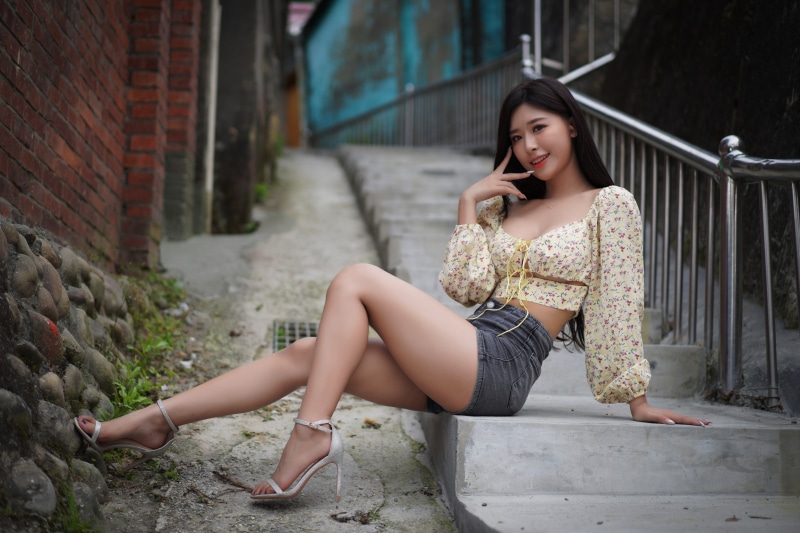 Asian woman in floral blouse and shorts posing on stairs