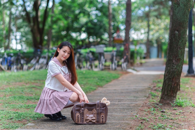 Asian schoolgirl with handbag posing outdoors