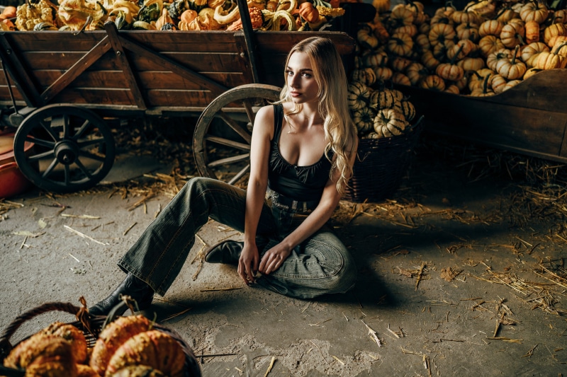 Blonde girl sitting with pumpkins