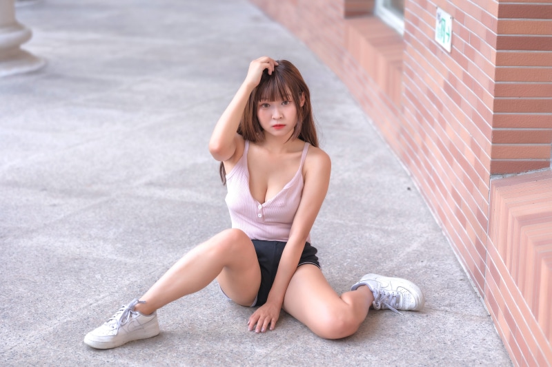 Asian woman sitting on the ground wearing a singlet and shorts