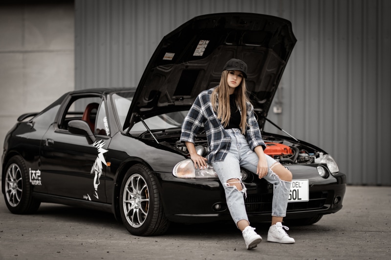 Girl in plaid shirt and ripped jeans sitting on Honda