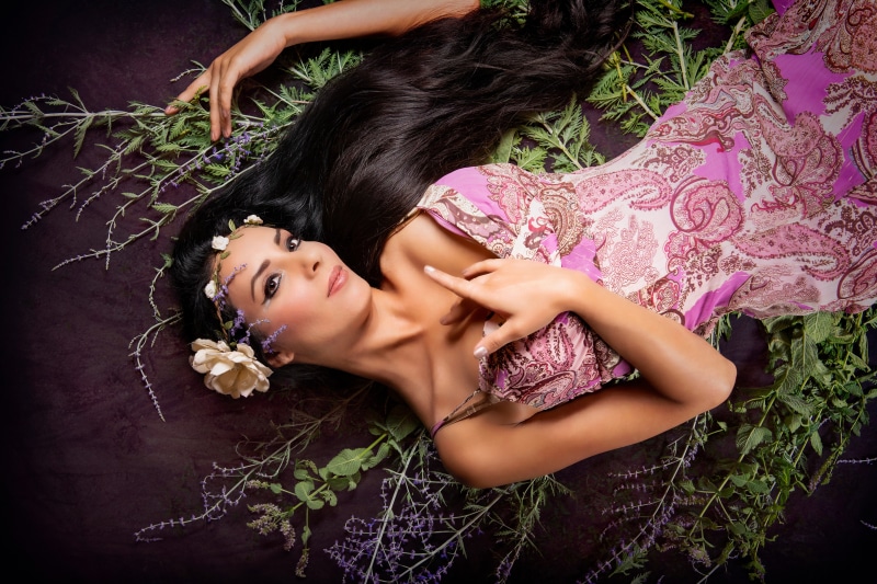 Brunette girl lying down with flowers and branches