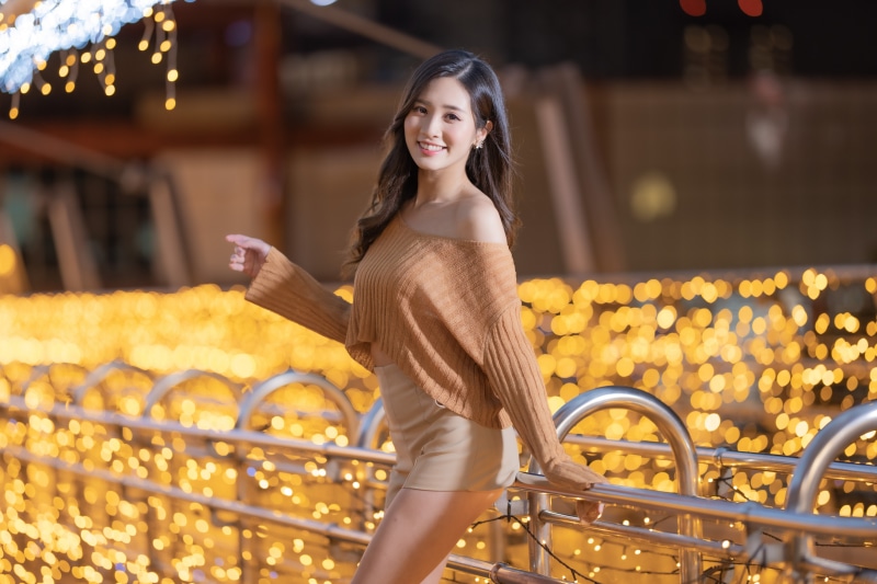 Asian woman smiling in off-shoulder sweater and shorts