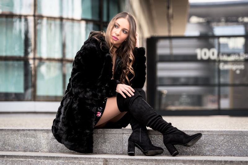 Woman in fur coat and boots sitting on steps
