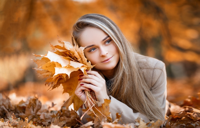 Woman with autumn leaves lying in foliage