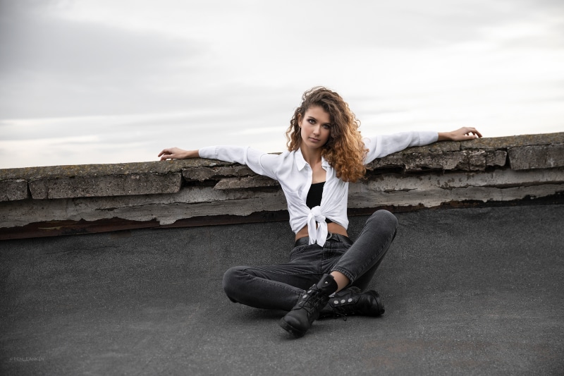 Woman with curly brown hair sitting on a rooftop