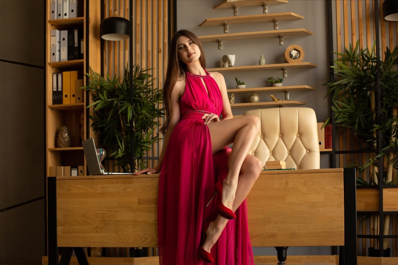 Woman in a pink dress sitting on a desk