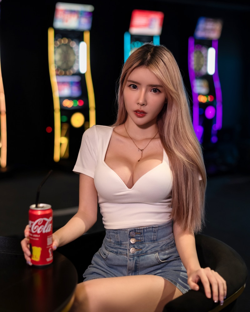 Woman in white top and denim shorts holding Coca-Cola