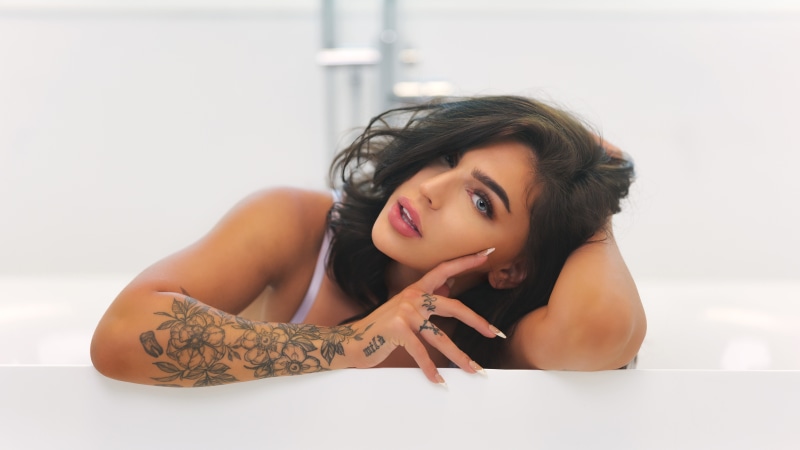 Brunette girl with tattoos in a bathtub